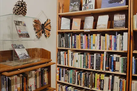 Wooden bookshelves filled with books and a display case with items on top.