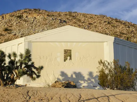 A large outdoor relief sculpture depicting the Last Supper set against a desert hillside.