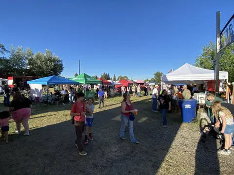 An outdoor market event with tents and people walking around.