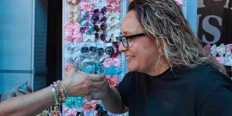 A person smells a bottle of perfume being held out to them.
