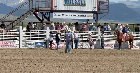 People and a horse gather at a rodeo arena.