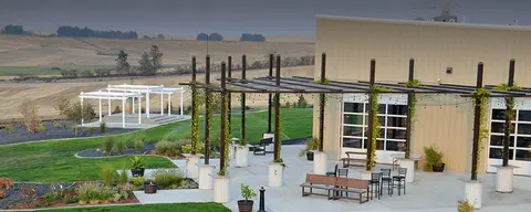 An outdoor patio area next to a building with rolling hills in the background.
