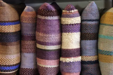 A row of colorful woven fabric bolsters is neatly arranged side by side.