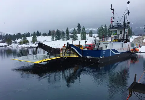 A cable ferry docked on a snowy riverbank.