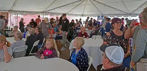 A large group of people gather under a tent for an event.