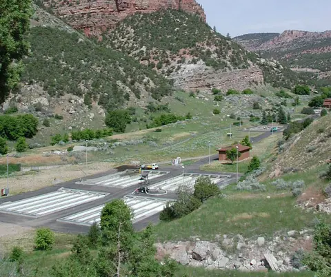 A water treatment facility nestled in a valley with mountains in the background.