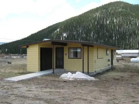 A yellow single-story building sits in front of a tree-covered mountain.