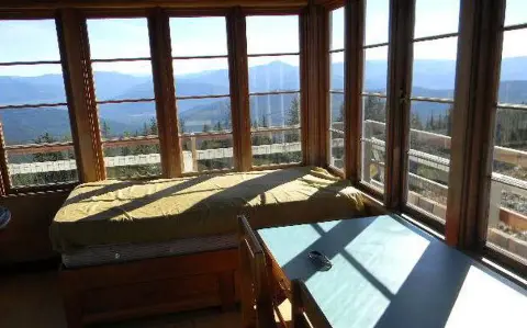 An interior view of a cabin with large windows showing a mountain landscape.