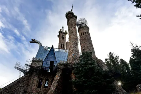 A unique stone castle with multiple towers and a dragon sculpture on the roof.