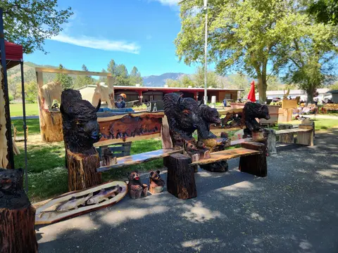 Wooden benches and sculptures carved with animals are displayed outdoors.