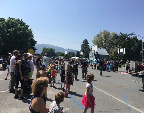 A crowd of people gathers outside for an event on a paved street.