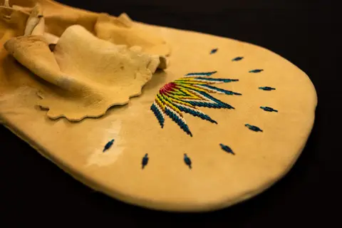A beaded leather pouch with colorful quillwork or beadwork design.