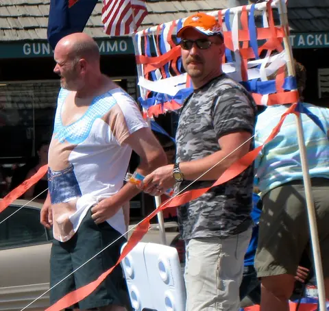 Two men stand near a decorated structure outside a building.