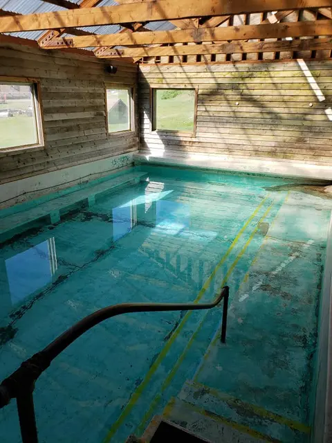 An indoor mineral pool with a rustic wooden structure and windows.