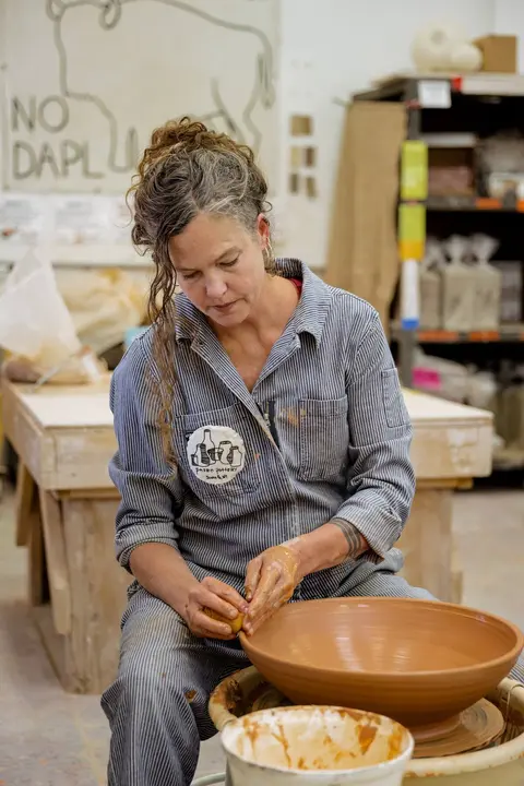 A woman working on a pottery wheel in a studio.