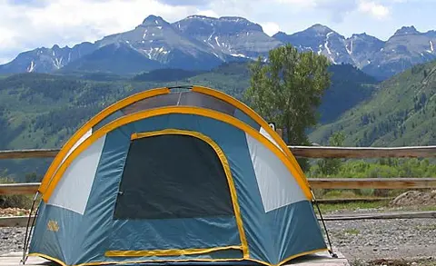 A tent is set up with mountains in the background.