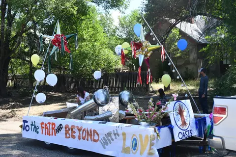 A decorated parade float on a trailer with star pinatas and balloons.