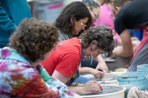 People working at pottery wheels in a workshop.