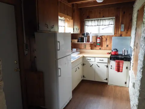 A rustic wooden kitchen with white cabinets and a refrigerator.