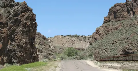A paved road leads through a rocky canyon between steep cliffs.