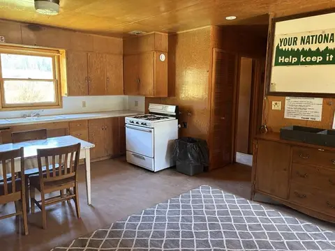 An interior view of a rustic kitchen with wood-paneled walls and a dining set.