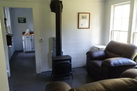 An interior room with a wood stove and leather armchairs.