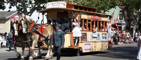 A horse-drawn trolley filled with people in costumes participating in a parade.
