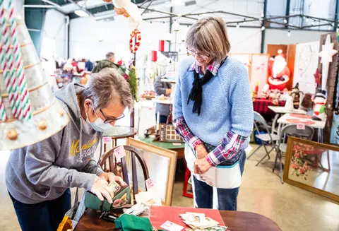 Two women shopping at an indoor craft fair.