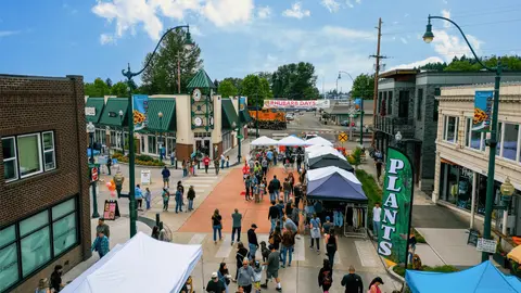 An elevated street view showing a community market event with tents and people gathered.