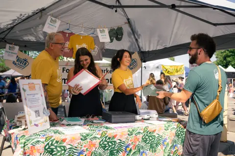 People at a market booth selling merchandise.