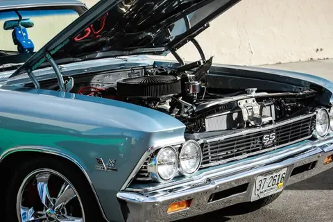 A classic car is shown with its hood open, revealing the engine.