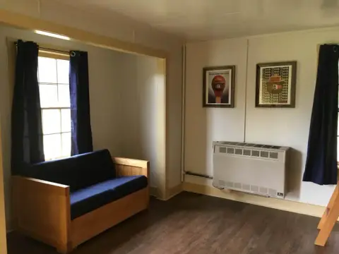 An interior room featuring a wooden couch and a window with blue curtains.