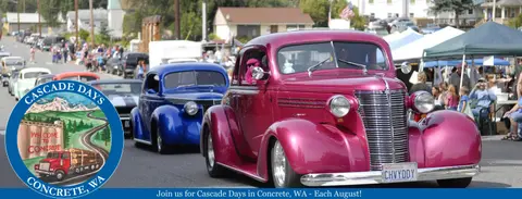 Classic cars drive in a street parade during a community event.