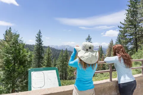Two women looking out at a mountain landscape from a scenic overlook.