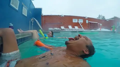 People relaxing in an outdoor swimming pool during winter.