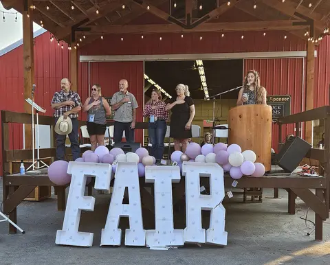 People stand on a stage with large letters spelling FAIR in front of them.