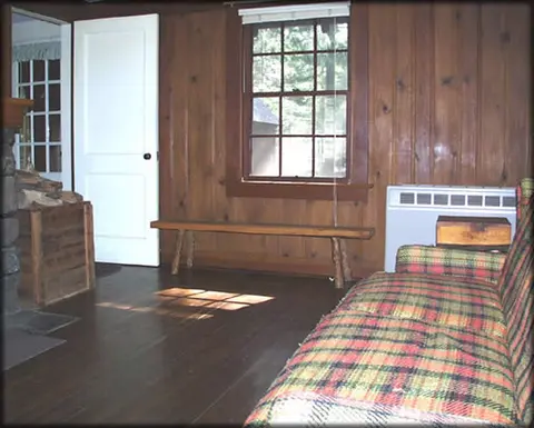 Interior view of a rustic room with wooden walls and a plaid couch.