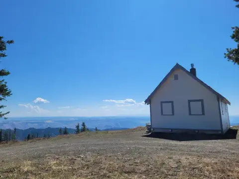 A small white building sits on a mountain peak under a clear blue sky.