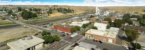 An aerial view of a small town with buildings, streets, and rolling hills.