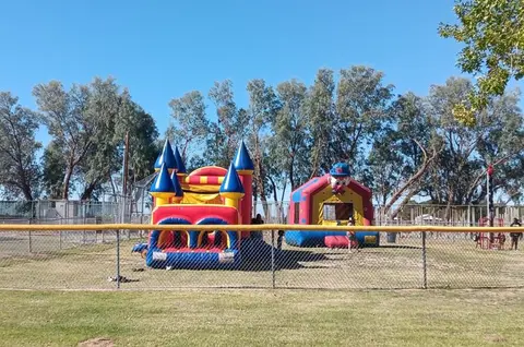 Two inflatable bounce houses are set up on a grassy field outdoors.