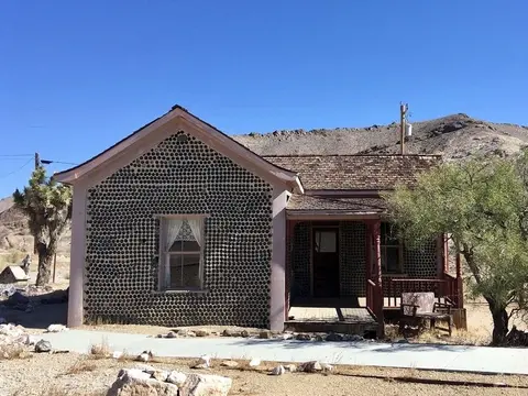 A historic house built with glass bottles in a desert landscape.