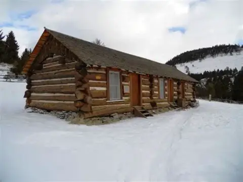 A long log cabin sits in a snowy landscape.