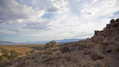 A wide view of a dry desert landscape under a cloudy sky.