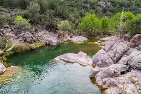 A clear stream flows through a rocky, green landscape.