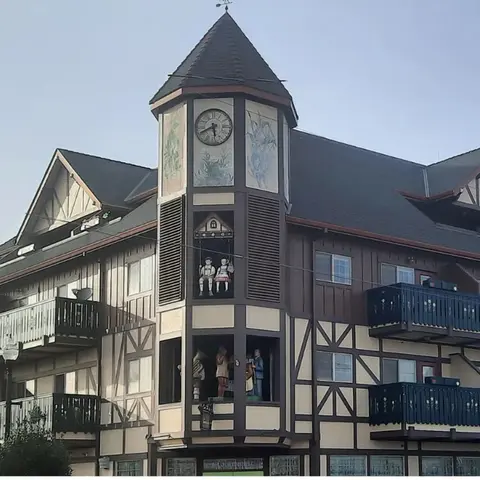 A building with a clock tower and alpine-style architecture featuring painted figures.