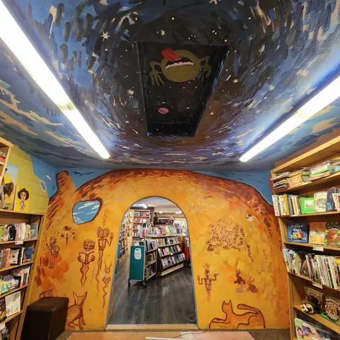 An interior view of a bookstore featuring a painted cave-like archway and ceiling.