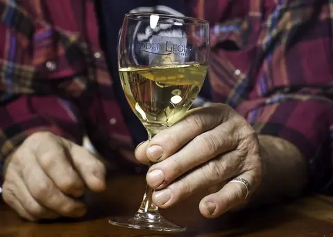 A person holds a glass of white wine.