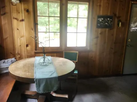 An interior shot of a room with wood-paneled walls, a round table, and windows.