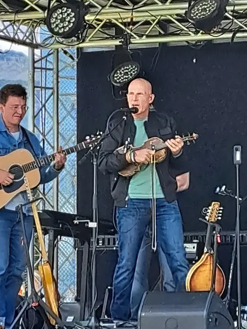 Two musicians perform on an outdoor stage.