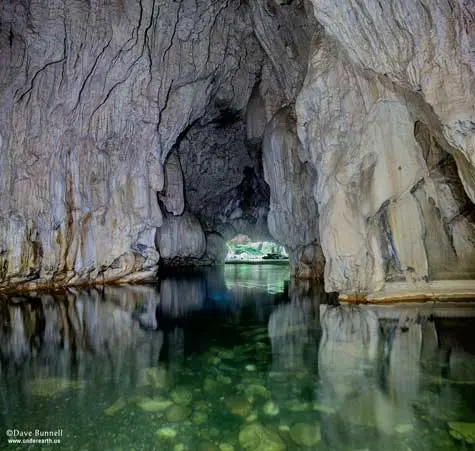 A view inside a cave with clear water reflecting the rock formations.
